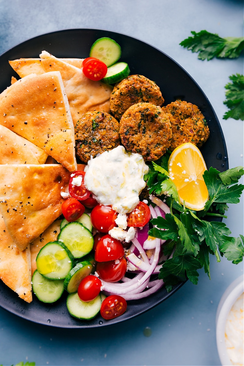 Overhead image of the Air Fryer Falafel, pita triangles, tzatzki, and raw veggies on a plate
