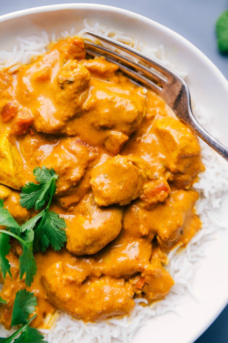 Close-up shot of a plate of Butter Chicken, with a fork on the side.