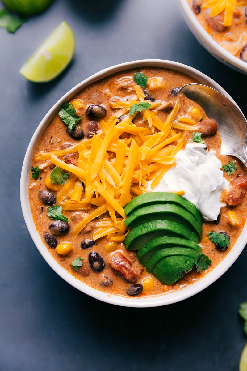 Overhead image of Chicken Chili with shredded cheese, sour cream, and avocado added on top.