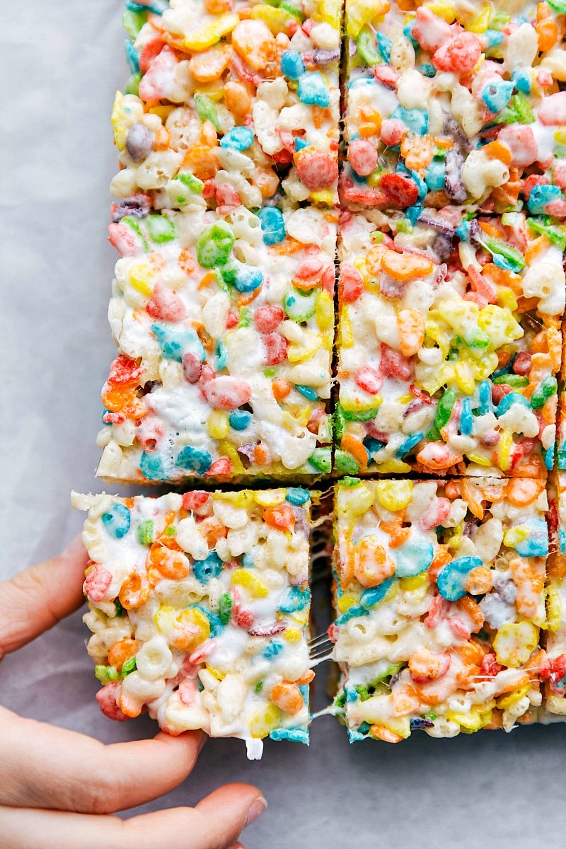 Child's hand pulling a Fruity Pebbles Rice Krispie Treat from all the other bars.