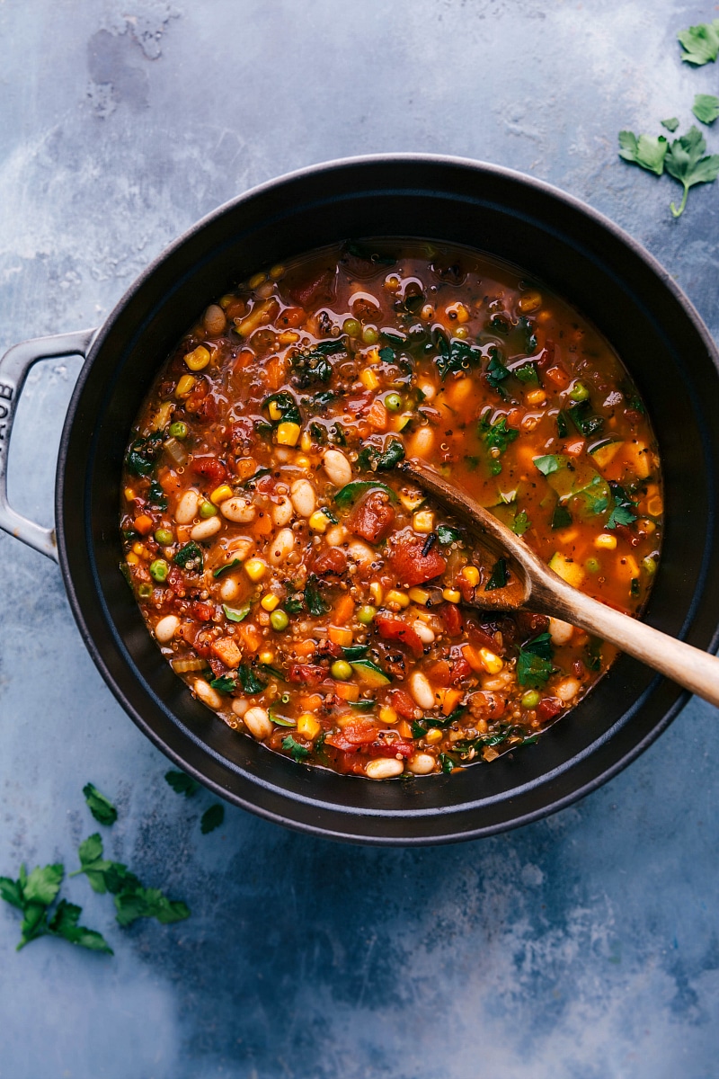 Overhead image of the pot of Healthy Minestrone Soup with a big wooden spoon in it.