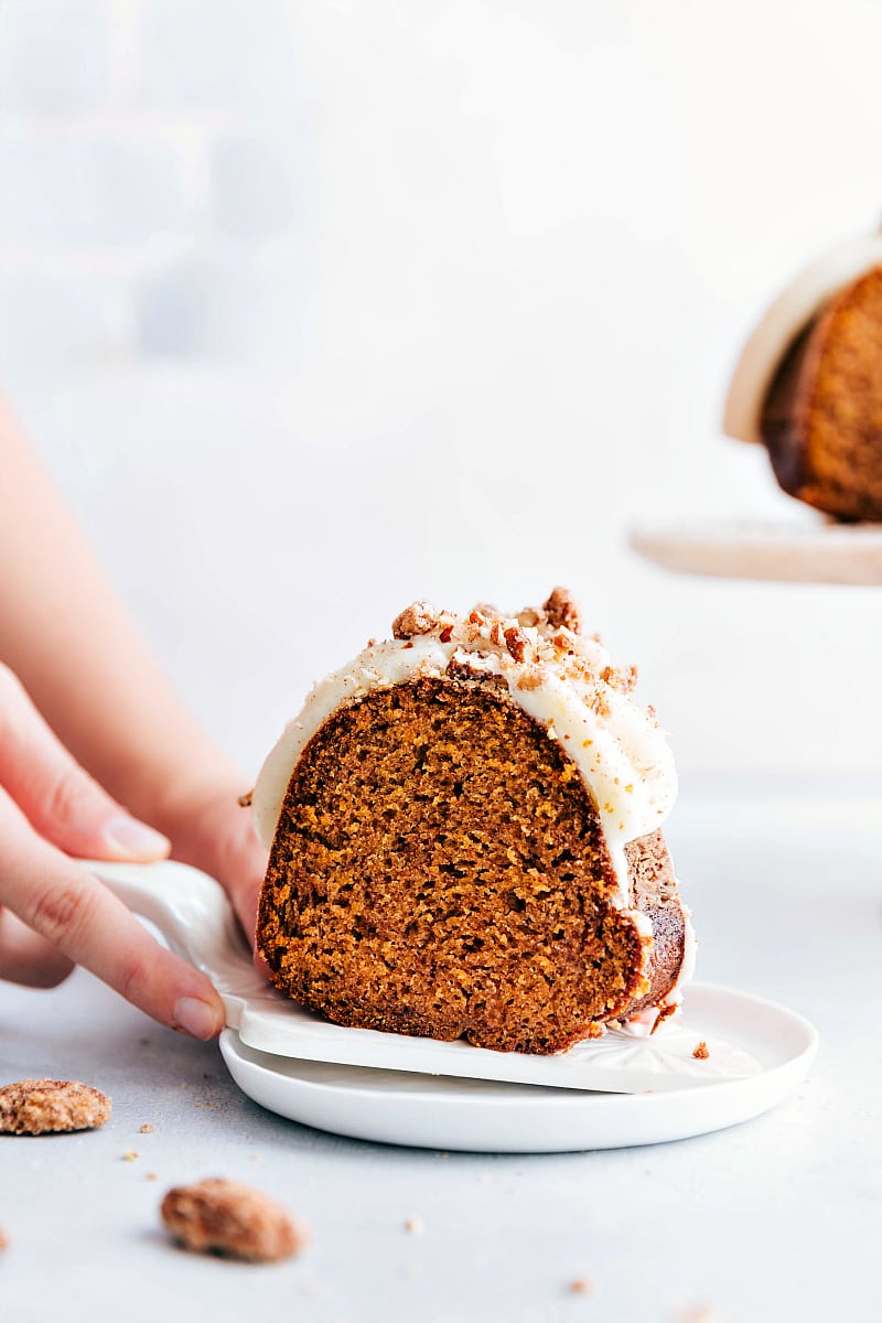 Up-close shot of a slice of Pumpkin Cake with cream cheese frosting, being served onto a plate.