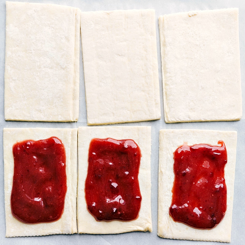 Process shot-- image of the puff pastry pieces with jam added to the center. 